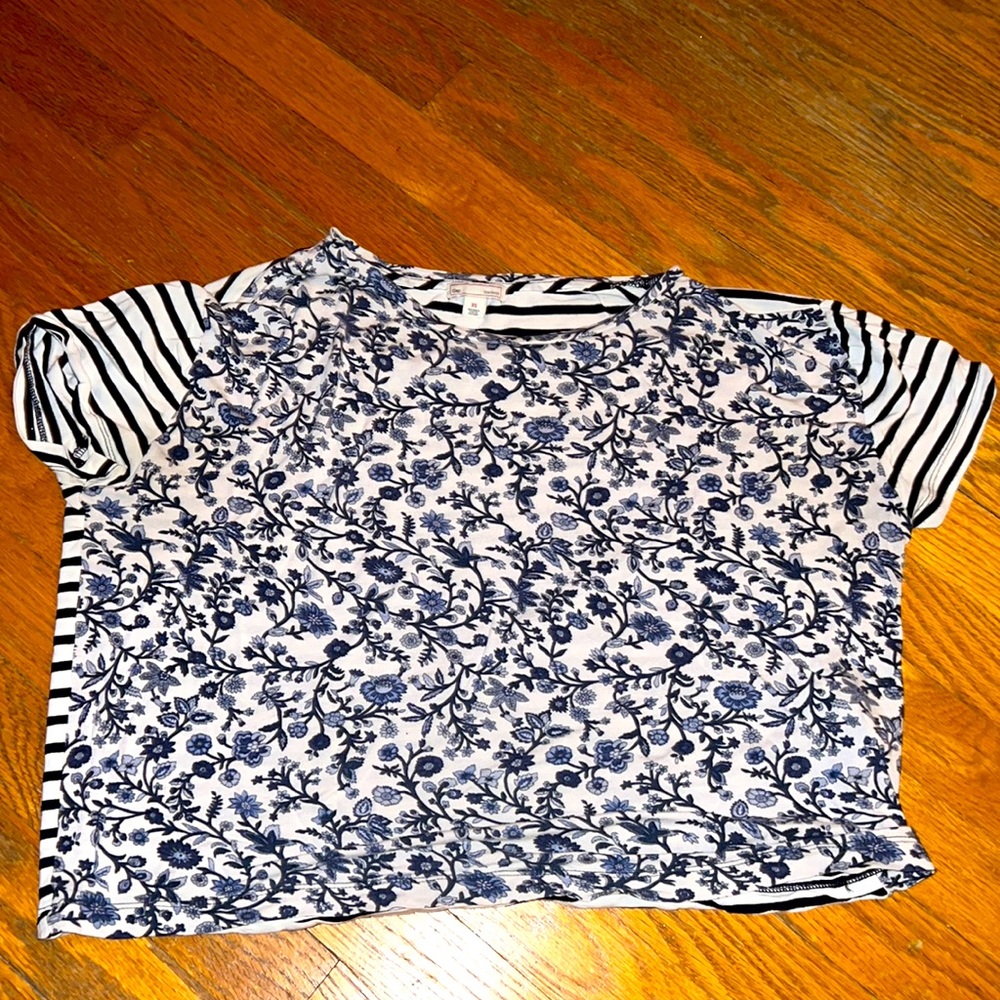 A t-shirt with a blue flower design and the back with a striped blue design.